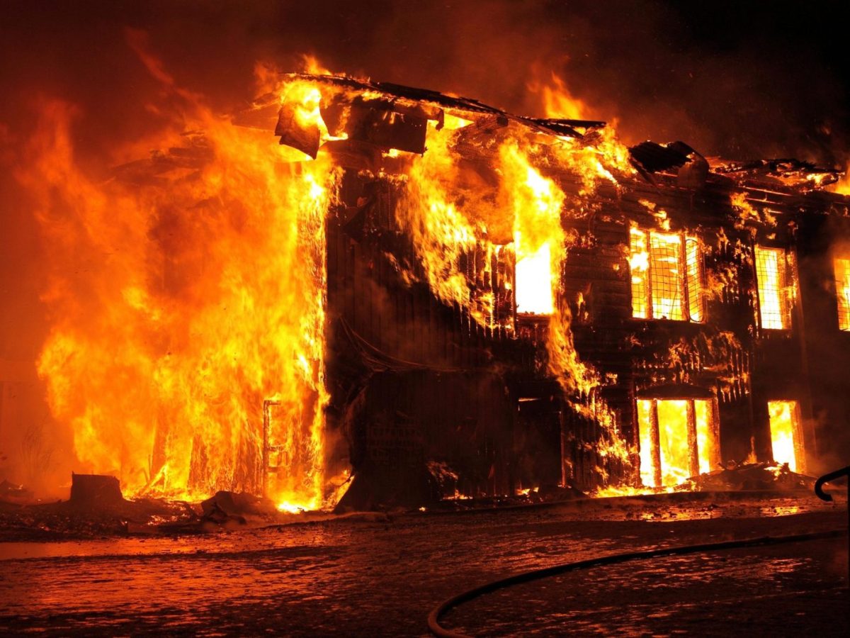 A dramatic nighttime scene of a house engulfed in flames in Tulan, Russia.