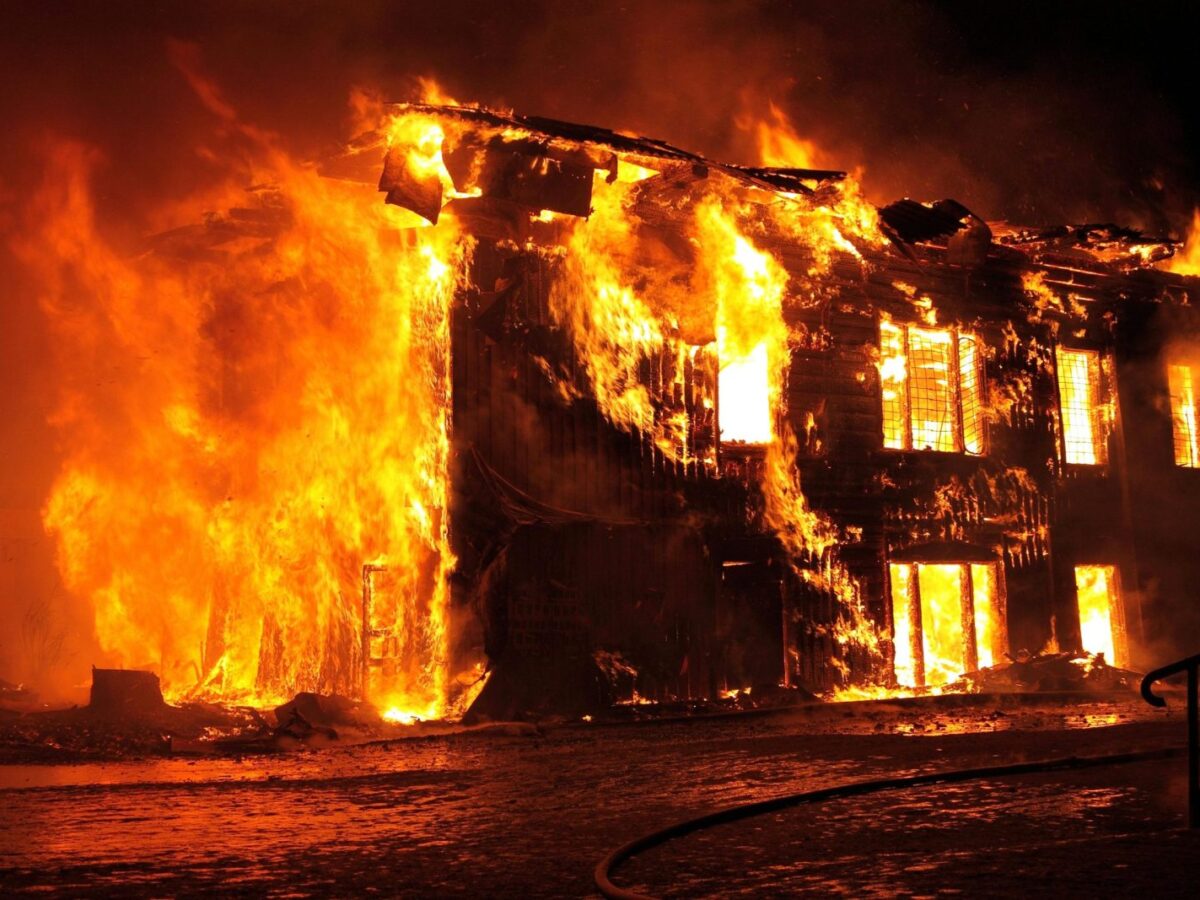 A dramatic nighttime scene of a house engulfed in flames in Tulan, Russia.