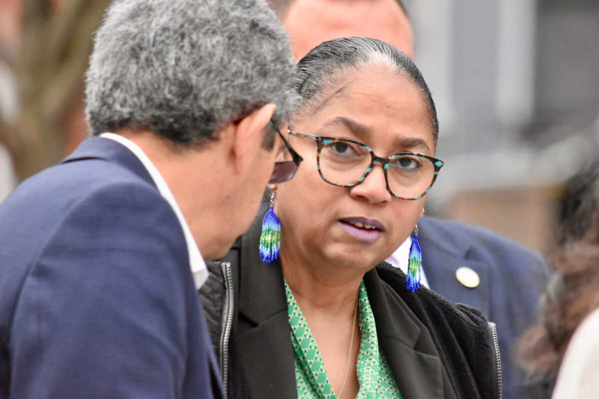 Woman in glasses and blue earrings speaking with a man in a suit outdoors
