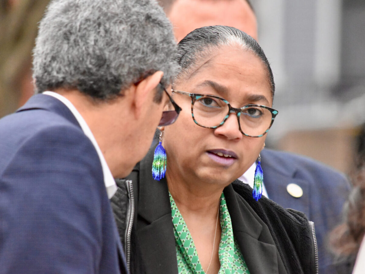 Woman in glasses and blue earrings speaking with a man in a suit outdoors