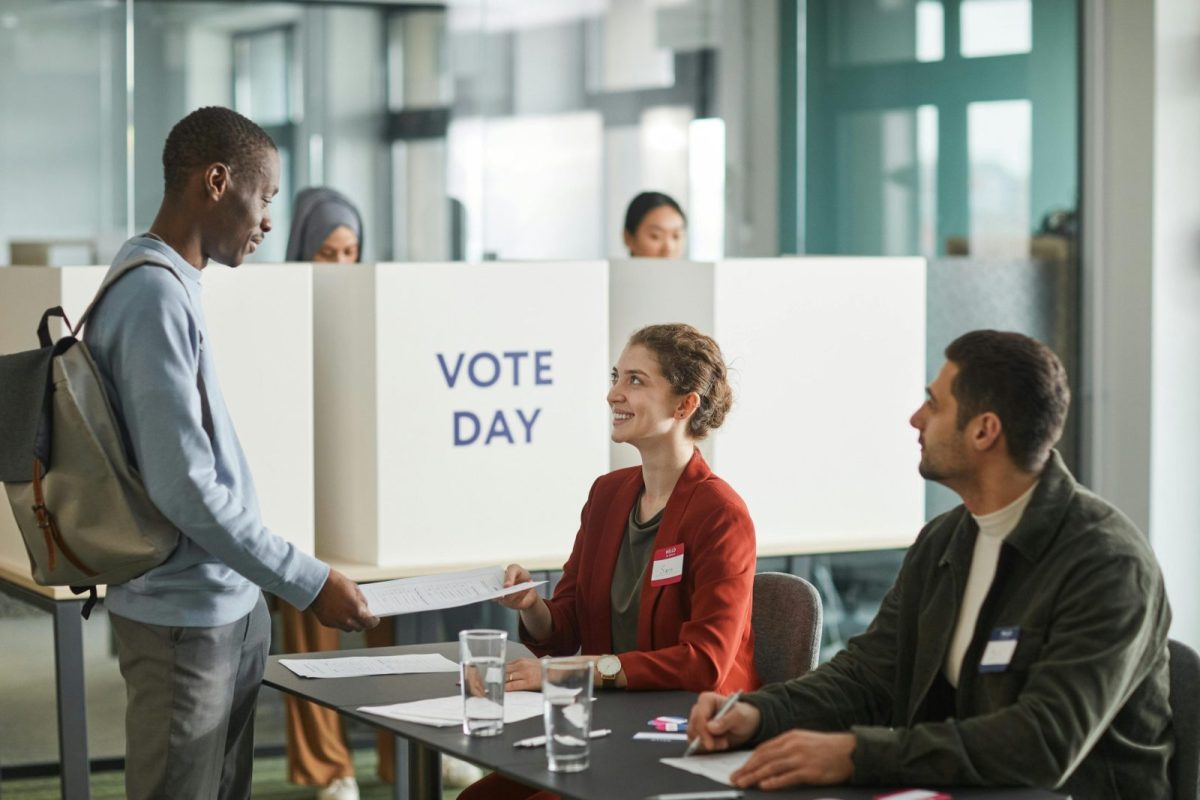 Diverse group of voters and officials at an indoor polling station on voting day.