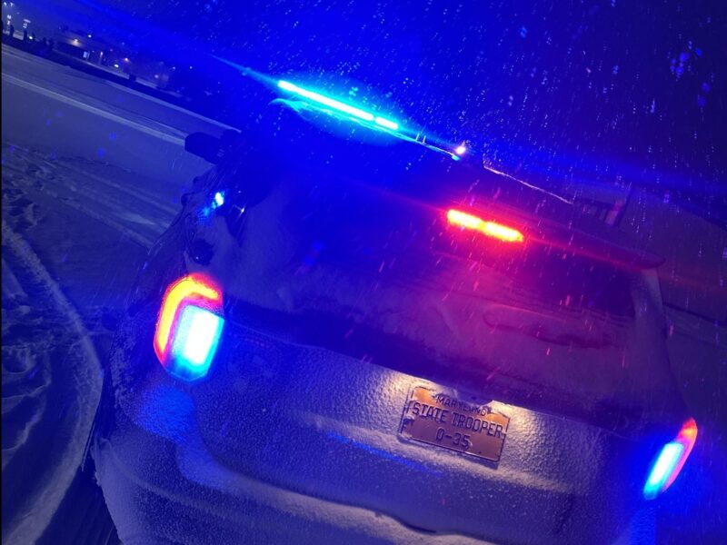 State trooper SUV with flashing blue and red lights on a snowy road at night