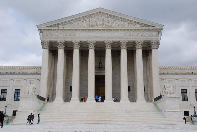 Supreme Court building with grand columns and wide marble steps under a cloudy sky.