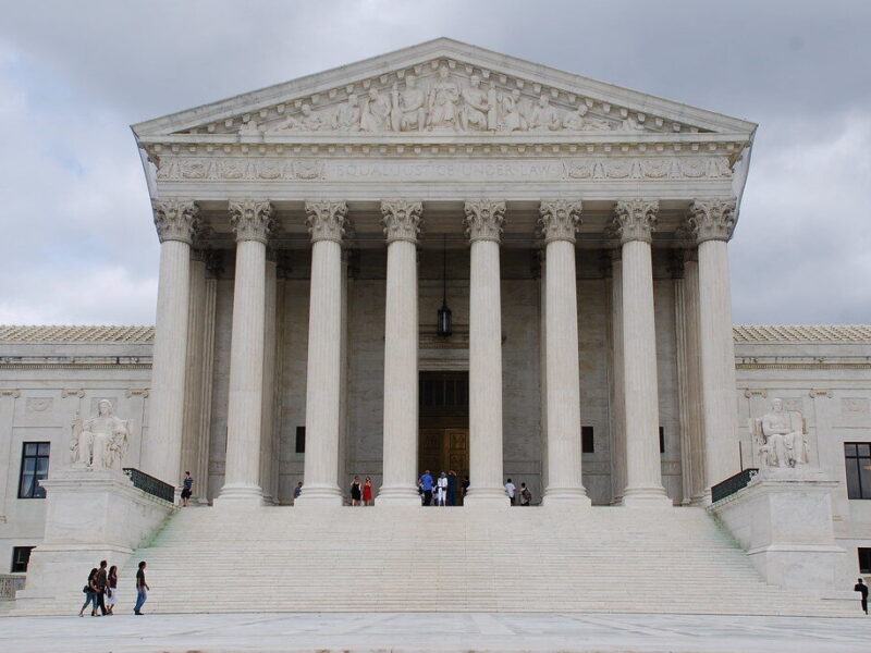 Supreme Court building with grand columns and wide marble steps under a cloudy sky.