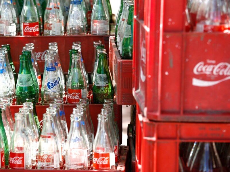 Stacks of glass Coca-Cola and Fanta bottles in red plastic crates.