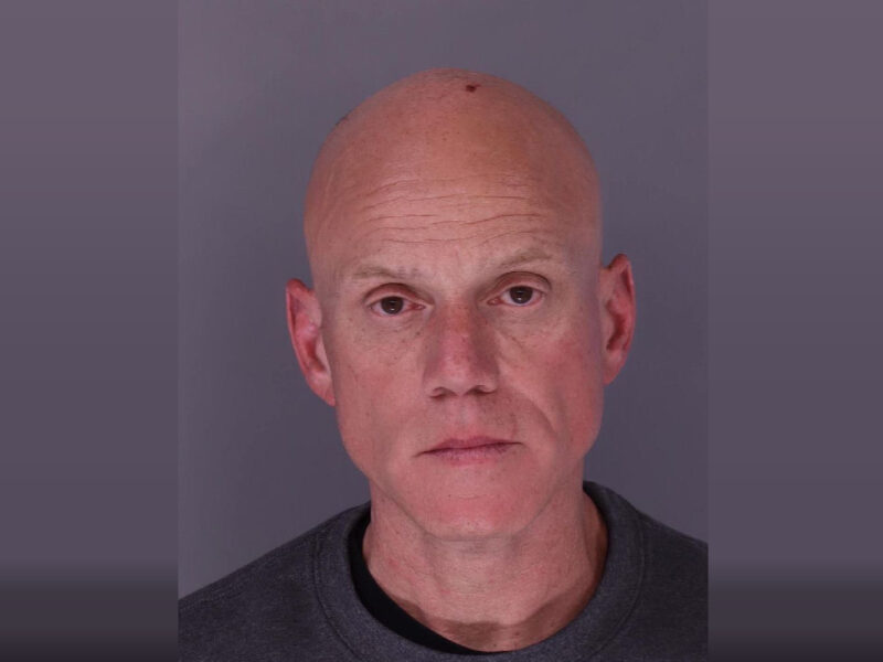 Portrait of a bald man against a plain gray background with a neutral expression.