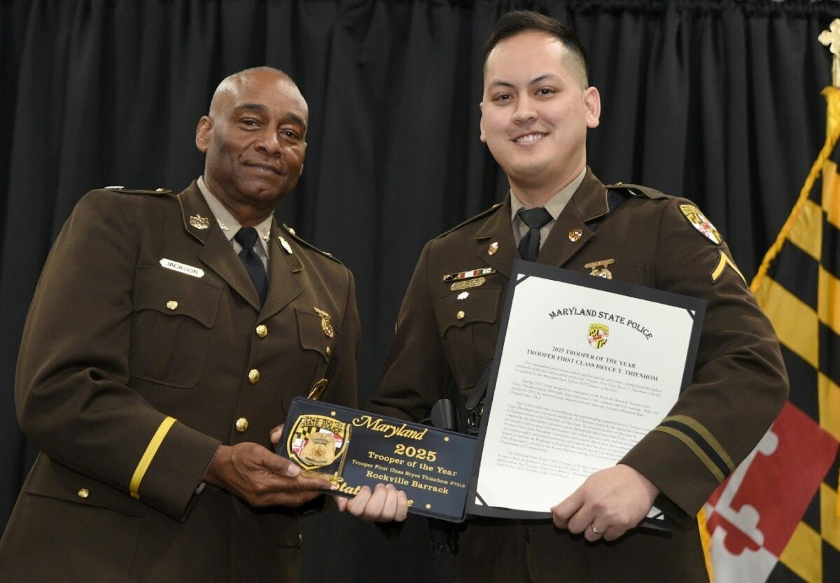 Two uniformed Maryland State Police officers hold a plaque and certificate at a ceremony.