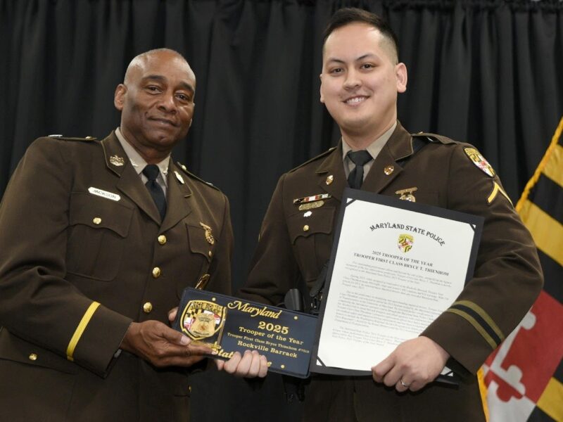 Two uniformed Maryland State Police officers hold a plaque and certificate at a ceremony.