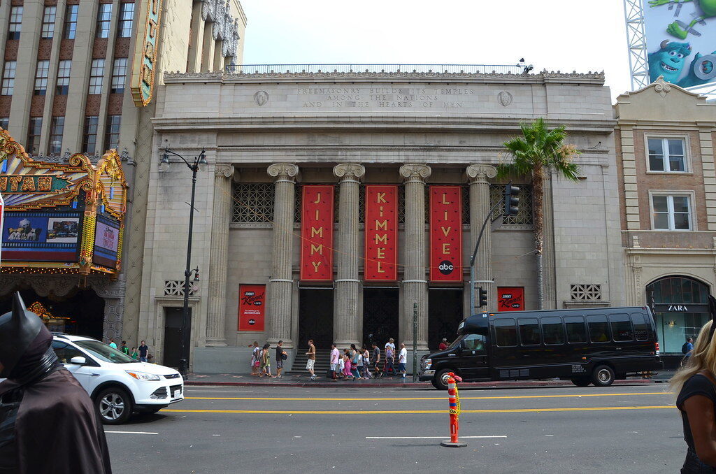 Historic theater facade with red banners and pedestrians on a city street.