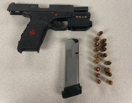 Handgun with magazine and loose bullets laid out on a speckled tabletop.