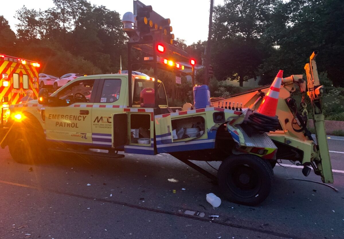 Emergency patrol tow truck with flashing lights and traffic cone after roadside incident at dusk.