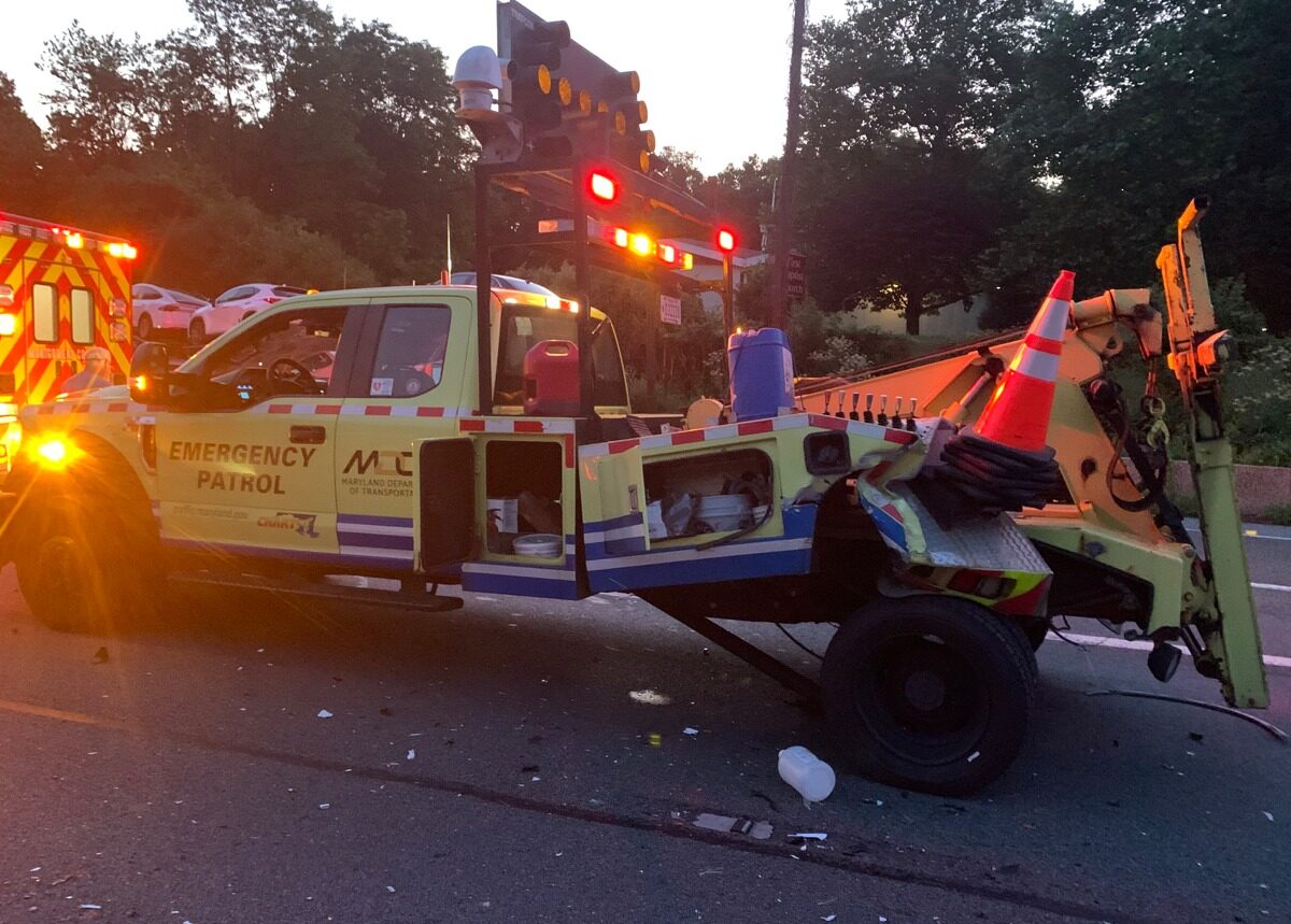 Emergency patrol tow truck with flashing lights and traffic cone after roadside incident at dusk.