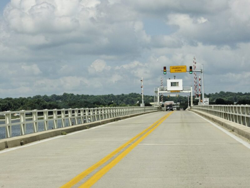 Empty concrete bridge stretches toward a checkpoint under cloudy skies.