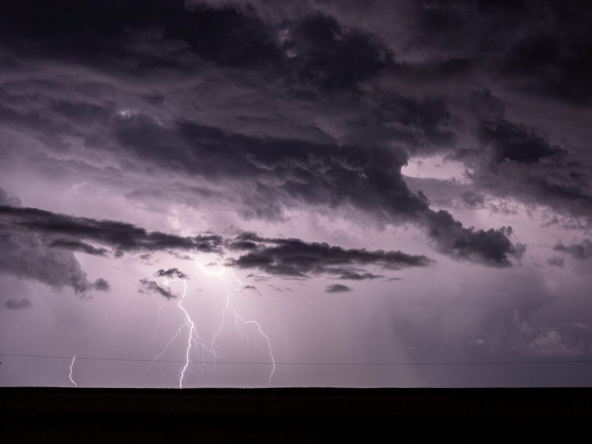 Dramatic stormy sky with intense lightning strikes illuminating dark clouds.