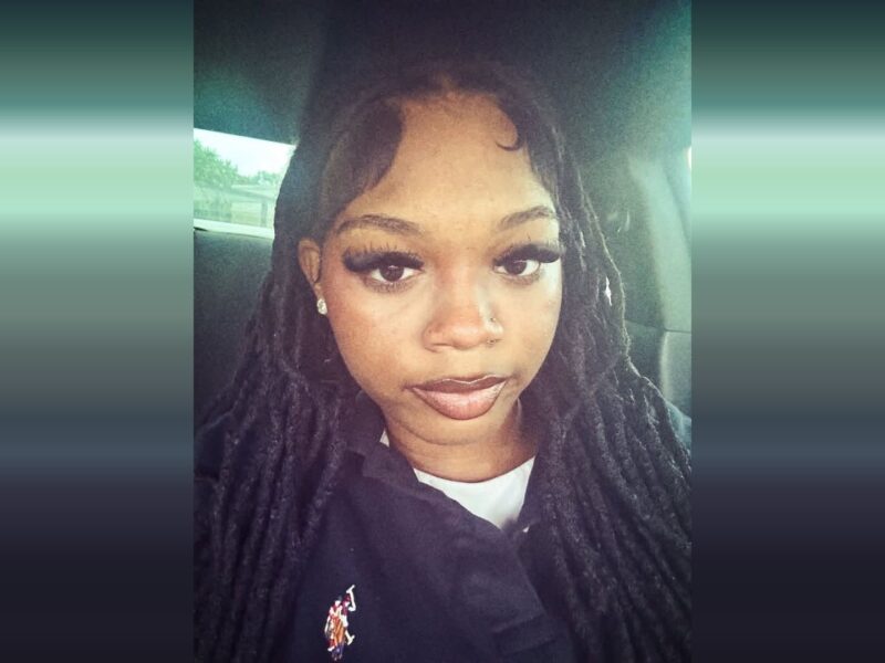 Selfie of a woman with long braids sitting in a car, wearing a black top.