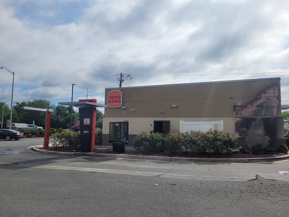 Abandoned Burger King restaurant with peeling exterior paint beside an empty drive-thru lane under a cloudy sky.