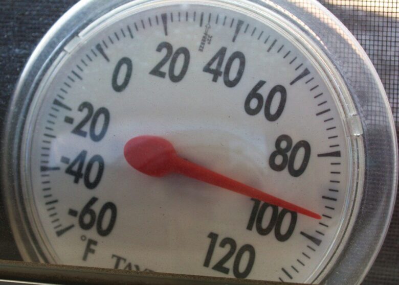 Close-up of a round analog thermometer showing about 100°F.