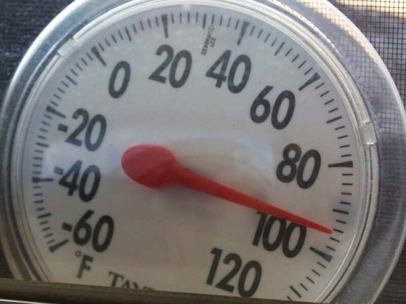 Close-up of a round analog thermometer showing about 100°F.