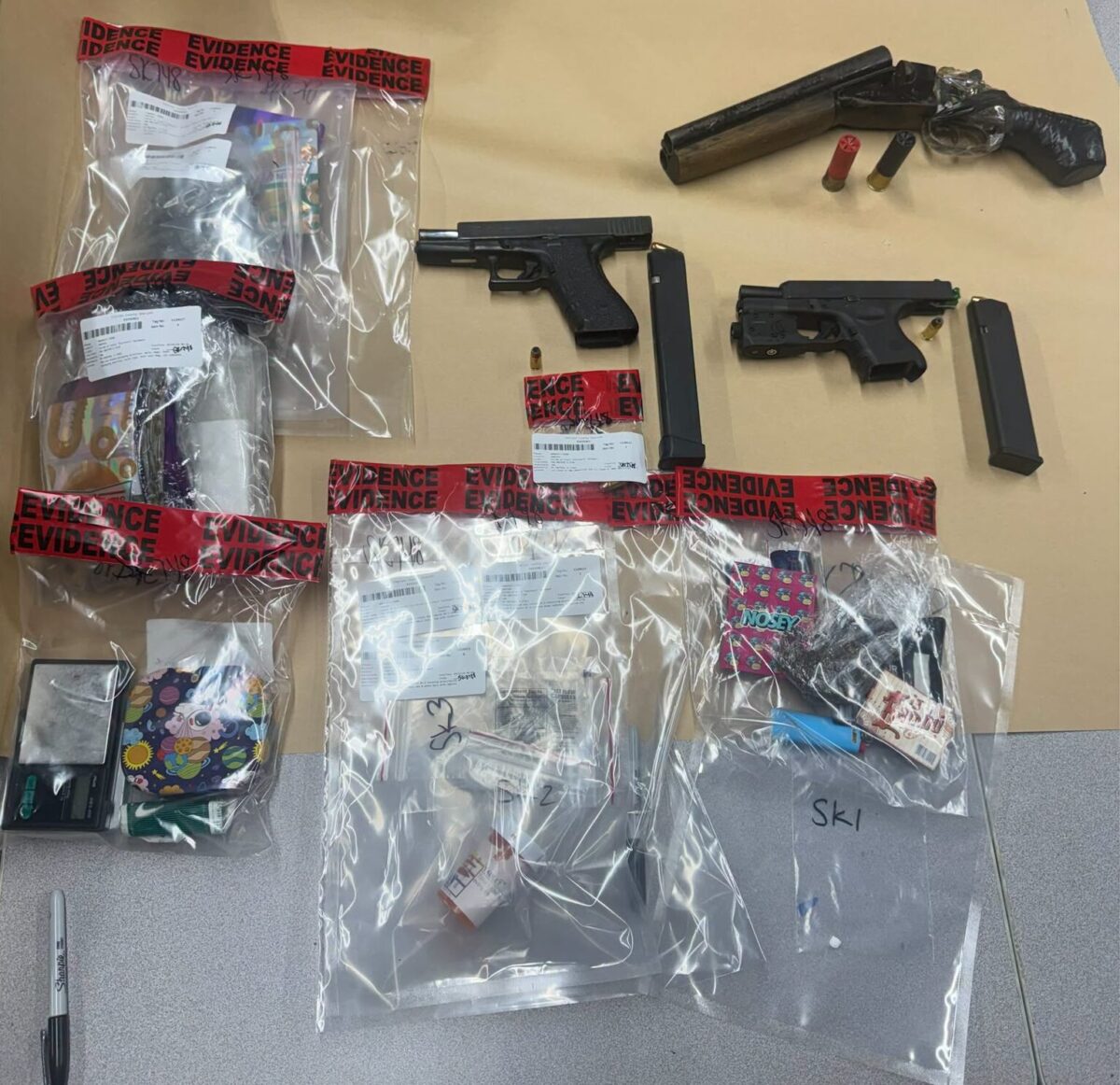 Firearms, ammunition, and seized items sealed in evidence bags on a table.