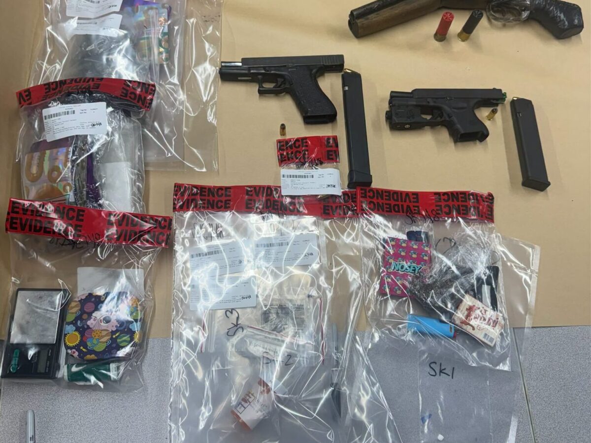 Firearms, ammunition, and seized items sealed in evidence bags on a table.