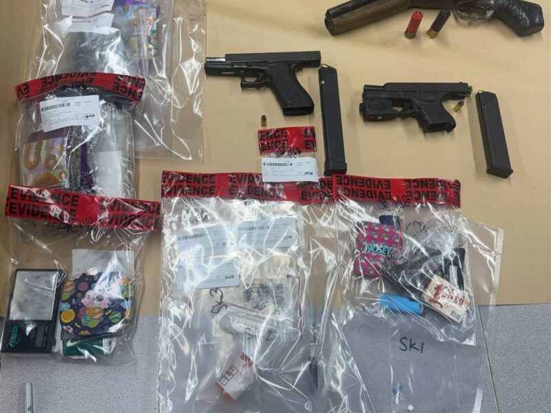 Firearms, ammunition, and seized items sealed in evidence bags on a table.