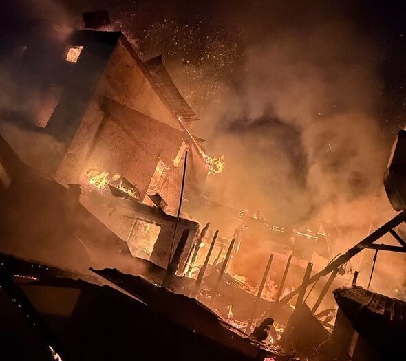 Burning building amid thick smoke and flames at night