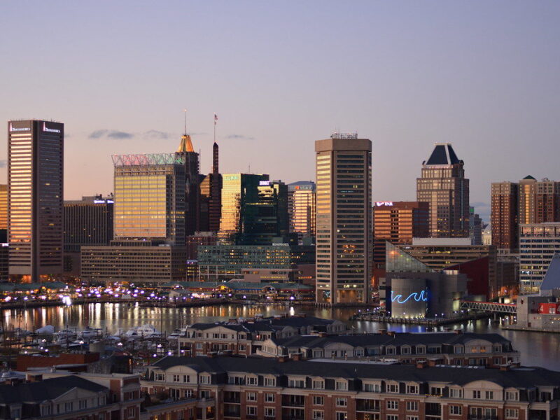 Sunset skyline of modern waterfront buildings with reflections on the water.