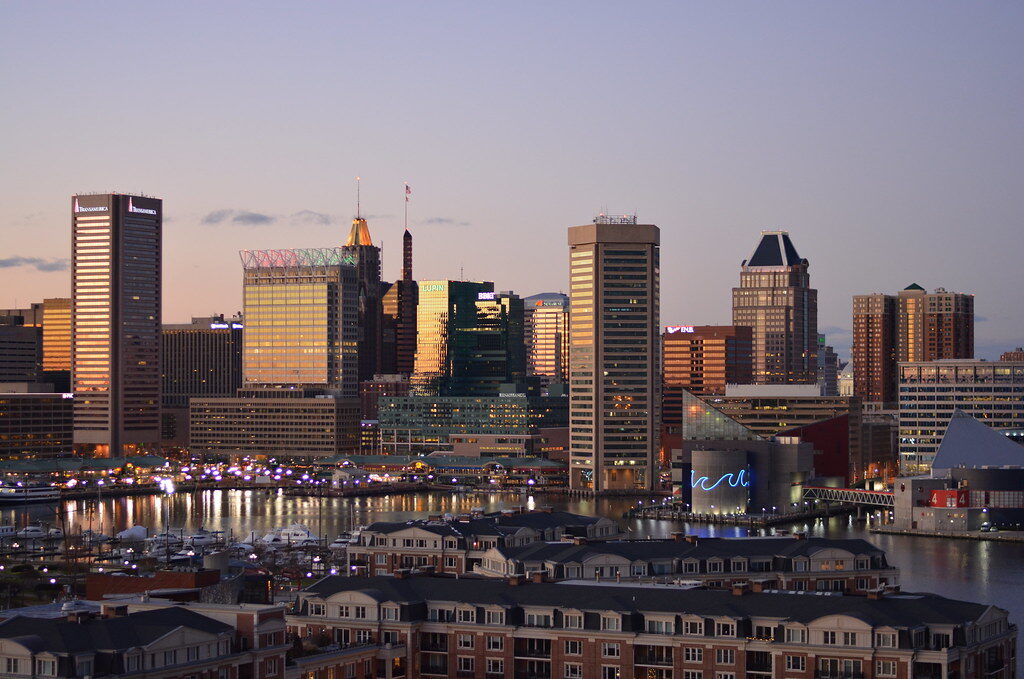 Sunset skyline of modern waterfront buildings with reflections on the water.
