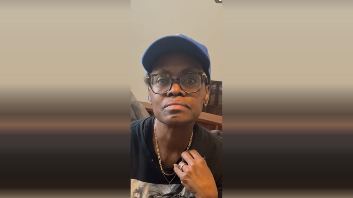 Person wearing glasses and a blue cap looks at the camera indoors.