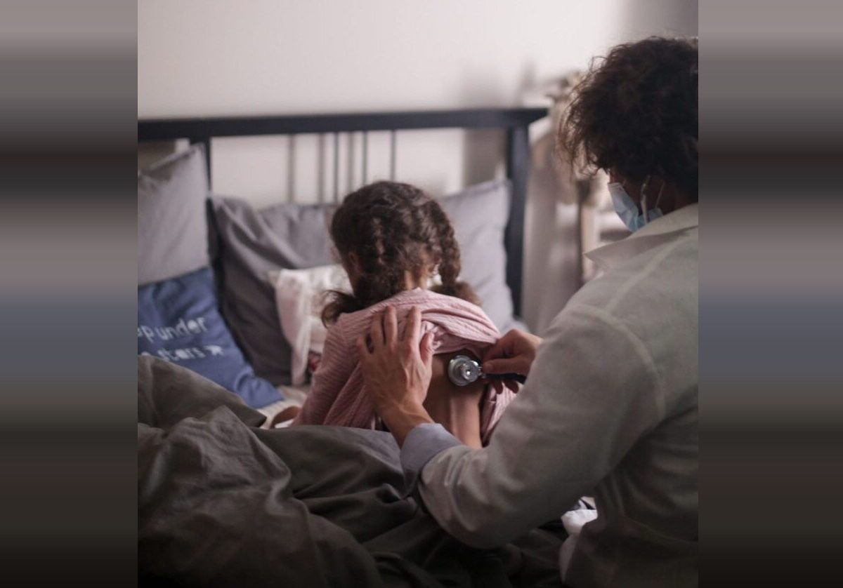 Parent checking a child’s back with a flashlight in bed.